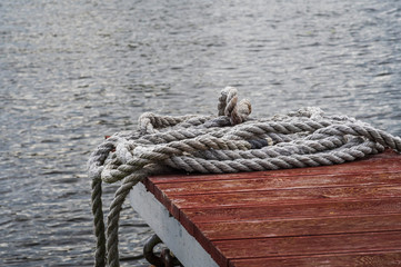 The rope lies on the pier against the background of water