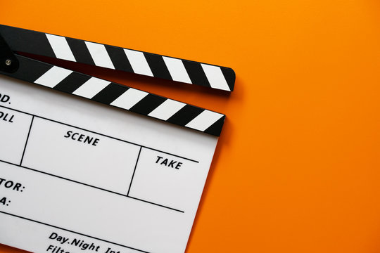 movie clapper on orange color table ; film, cinema and video photography concept