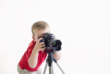 Little boy use large professional dslr camera on tripod on white background