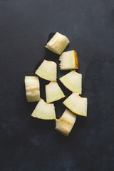 top view of fesh melon sliced pieces, cut on a black surface