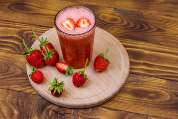 Glass of fresh strawberry smoothie on a wooden table