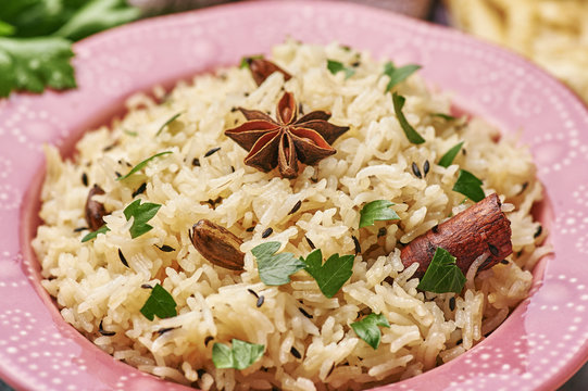 Jeera Rice in pink plate. Jeera rice - traditional indian cuisine dish with basmati rice, cumin, coriander, star anise and cardamon. Close up