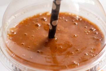 close up macro of fresh summer cooling fruit smoothie in glass with straw