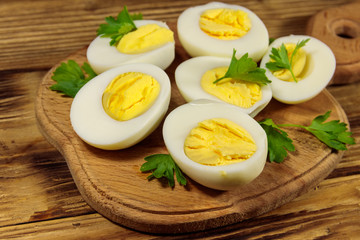 Boiled eggs with parsley on cutting board on a wooden table