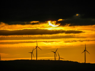 Obraz premium Sunset on the horizon over windmills with cloudy sky