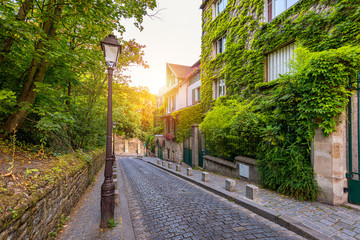 Fototapeta na wymiar Montmartre district of Paris. Houses on narrow road in Montmartre district of Paris. View of cozy street in quarter Montmartre in Paris, France. Architecture and landmarks of Paris. Postcard of Paris.