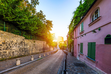 Obraz na płótnie Canvas Montmartre district of Paris. Houses on narrow road in Montmartre district of Paris. View of cozy street in quarter Montmartre in Paris, France. Architecture and landmarks of Paris. Postcard of Paris.
