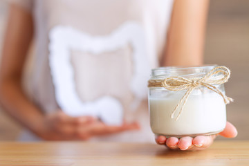 Female hand is holding jar with natural organic yogurt with bifidobacteria. Woman eat dairy...