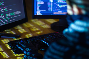 Back view of man woman in black gloves is hacking password. Programmer is writing malware on...