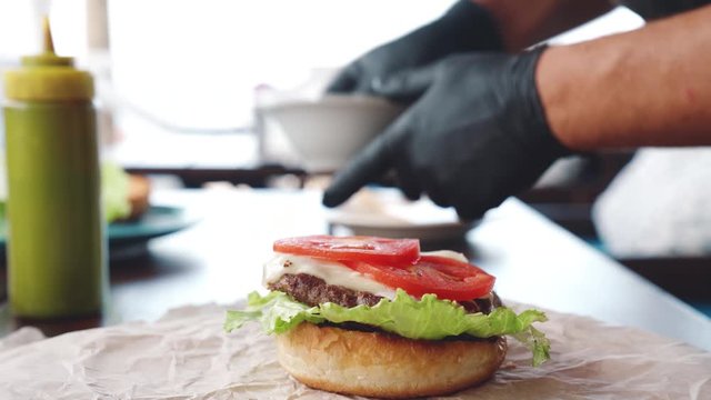 Chef cooking meat burger with cutlet, cheese and vegetables. Preparing delicious burgers.