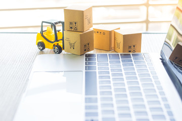 Mini forklift truck load cardboard boxes with text online shopping and symbols on laptop keyboard. Logistics and transportation management ideas and Industry business commercial concept. - obrazy, fototapety, plakaty