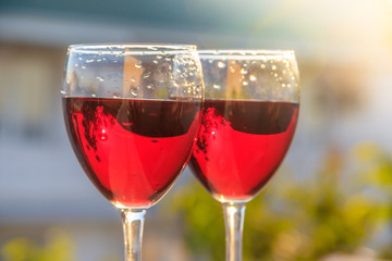 Two glasses of red wine are backlit by the sun. Grape drink.