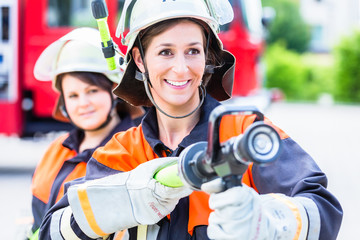 Female fire fighters spouting water to extinguish