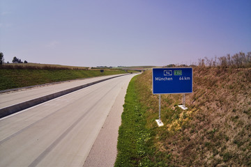 Autobahn A94 at Heldenstein with street sign distance to Munich 64 Km open up new highway