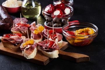 Spanish tapas with slices jamon serrano and grilled pepper. Also olives, salami, pickled onions, and peppers stuffed with cheese