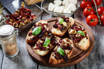 Obraz na płótnie Canvas Appetizer bruschetta with sun-dried tomatoes, olives and mozarella.