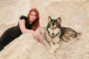 Funny best friends concept. Happy young female person walks in the desert with big dog malamute outdoors