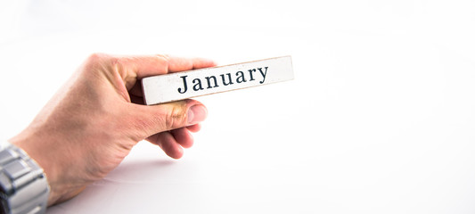 January - A hand holding calendar month block on white background