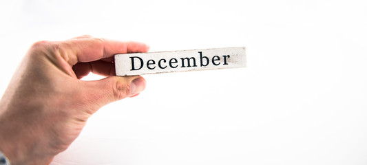 December - A hand holding calendar month block on white background