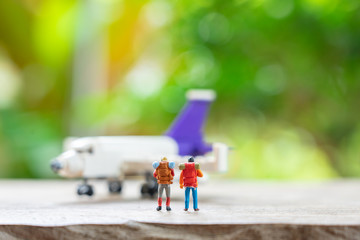Miniature 2 people standing travel planner with Plane model as background travel concept with copy space.