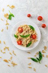Pasta with tomatoes and basil on a white plate. Italian traditional cuisine.