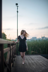 Romantic girl in black dress walking on pier