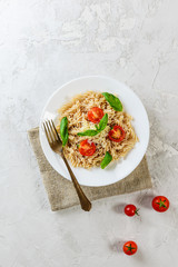 Pasta with tomatoes and basil on a white plate. Italian traditional cuisine.