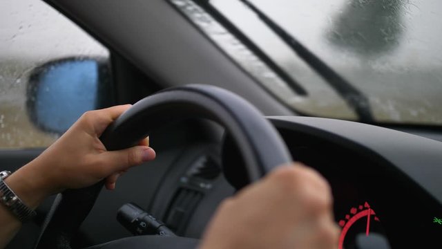 Car Dashboard and Female Hands Holding Steering Wheel When Driving in Heavy Rain