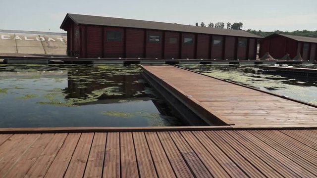 footage of camera moving along long wooden pier in the river at suny light.
