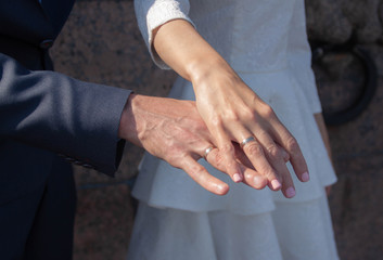 hands of the newlyweds with wedding rings on the finger, close up