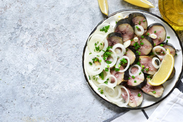 Smoked mackerel with onions and lemon on a concrete background. View from above.