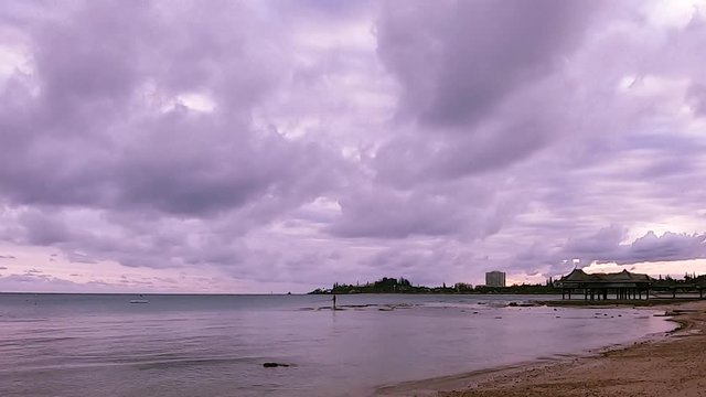 Moving clouds at sunset time lapse video on a slightly overcast evening at the tropical beach -Anse Vata Bay in Noumea, New Caledonia, French Polynesia, South Pacific.