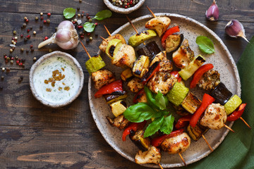 Grilled chicken fillet and vegetables. Barbecue of chicken on skewers with vegetables on wooden...
