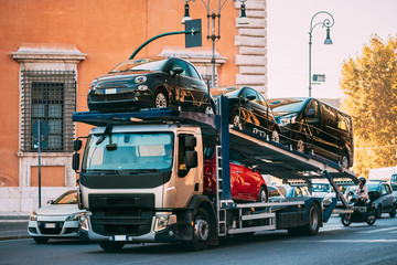 Auto-transport Carrying New Fiat Cars In European City Street. Auto Transport Broker Or Car Transporter