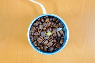 old vintage electric coffee grinder with fresh coffee beans on the wooden background. electric grinder with whole grains of coffee. Grinding in electric mill. Close up.