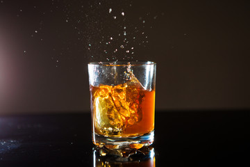 Glass of whiskey with splash on black background