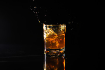 Shot of whiskey with splash on black background
