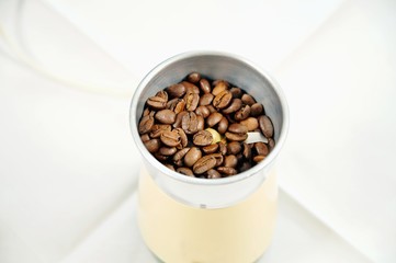 old vintage electric coffee grinder with fresh coffee beans on the white background. electric grinder with whole grains of coffee. Grinding in electric mill. Close up.