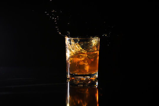 Shot Of Whiskey With Splash On Black Background