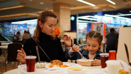 Cute little girl with young mother in restaurant