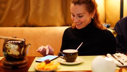 Smiling businesswoman drinking coffee and using chating in a office.