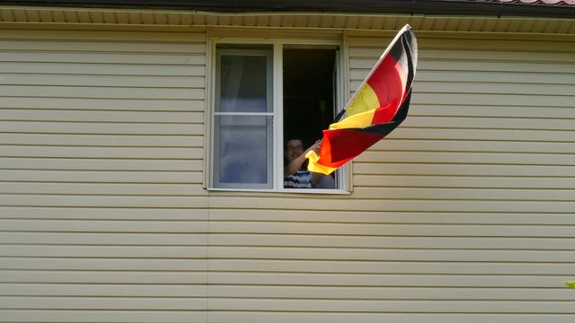 Young people waving a flag in a window at home