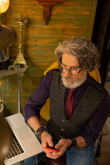 Serious man thinking of calling his coworker.