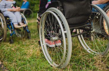 Disabled man resting in a campsite with friends. Wheelchair in the forest on the background of tents