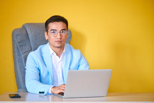 Asian Kazakh businessman in a suit and glasses with a laptop computer works in the office, a successful professional manager solves business issues