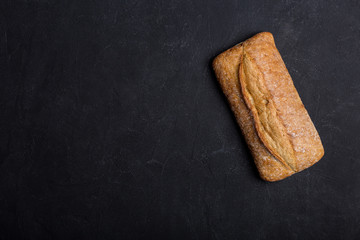 Beautiful tasty loaf of grain bread on black background