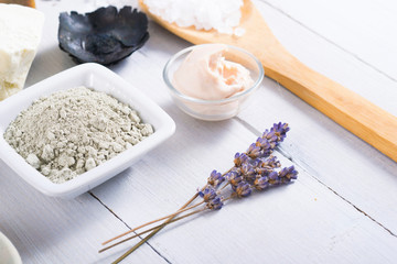 spa massage mud and clay powder, soaps, bath salt, shea butter and lavenders on white wood table background