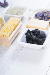 spa products: black mud and clay powder, cosmetic cream, soap, bath salt, shea butter and lavenders on white wood table background