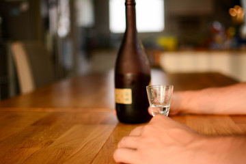 alcoholism, alcohol addiction and people concept - male alcoholic with bottle and glass drinking whiskey at home.