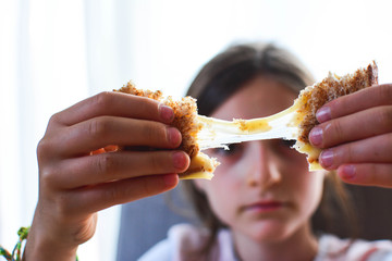 Grilled cheese sandwich. The girl pulls a delicious fragrant cheese out of a sandwich.